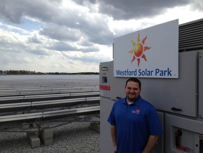 GEI employee standing in front of Westford Solar Park sign